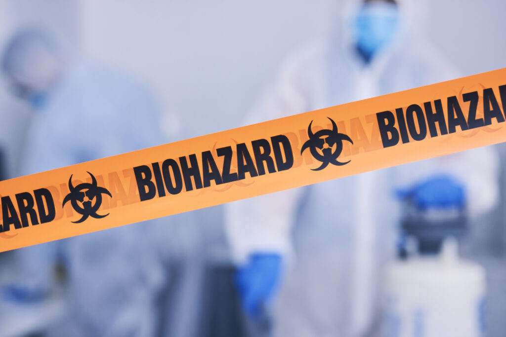 Biohazard, tape and people with caution working with toxic, biology or team disinfect dangerous bacteria or for health crisis. Hazard, protection and warning for bio safety or cleaning in hazmat suit