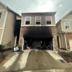 Residential home garage damaged by fire with visible soot and smoke staining