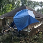 Residential property with roof tarp following storm damage