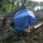 Residential property with roof tarp following storm damage
